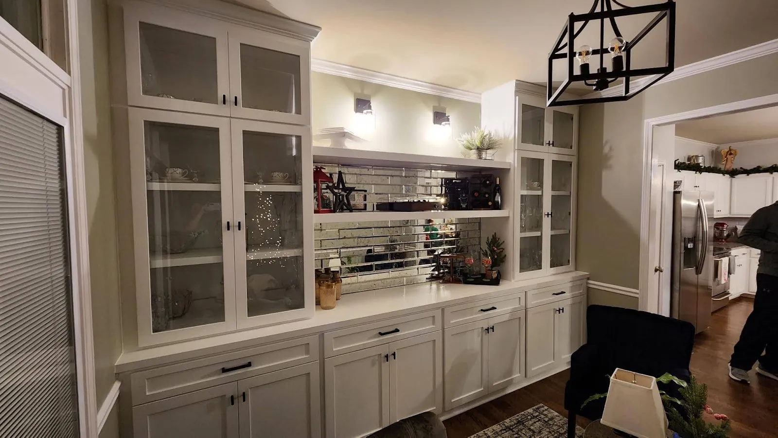 Cream library cabinetry with mirrored backsplash, glass doors and shelving