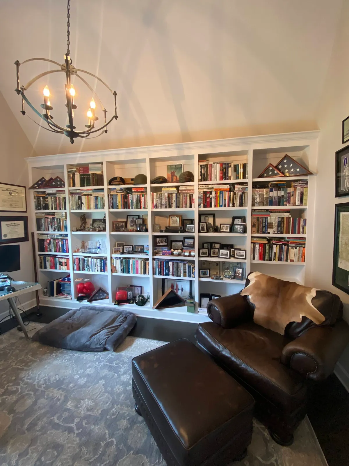 White built-in library shelving with display nooks and brass pendant lighting