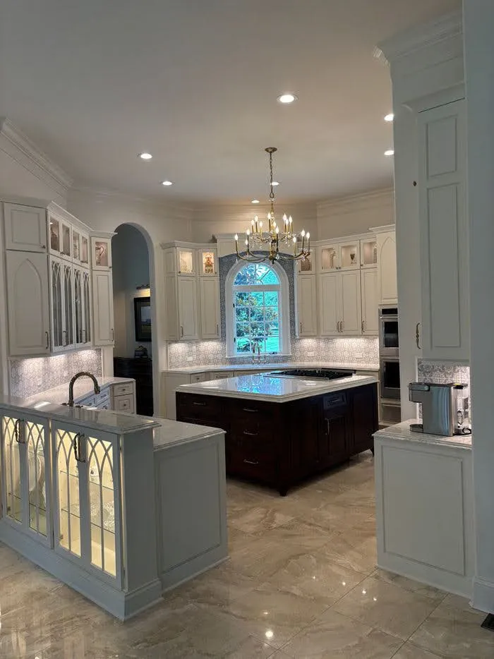Luxe kitchen with white cabinetry, black island and gas-range archway